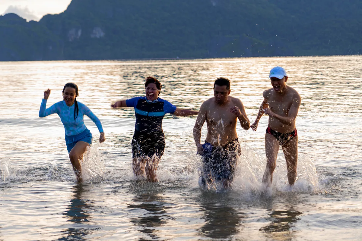 Team splashing joyfully in the sea at golden hour